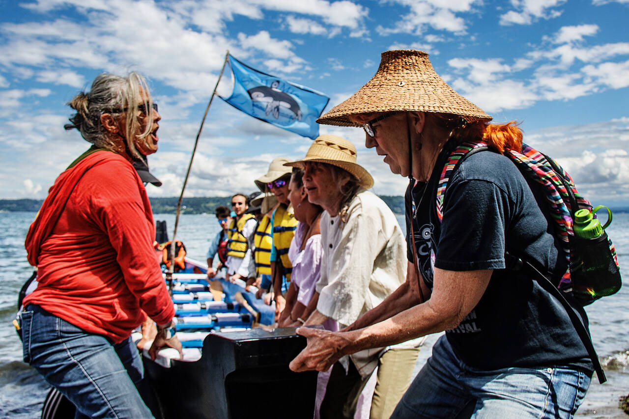 The Blue Heron Canoe Family pull a canoe up onto the beach after arriving at Sandy Point on Whidbey Island. (Photo by David Welton)