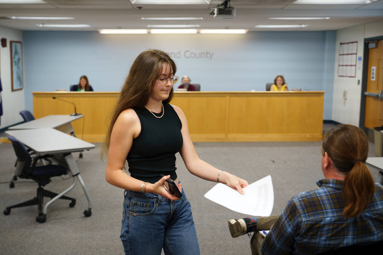 Photo by David Welton
Annie Philp distributes materials related to the United Student Leaders’ plea for county commissioners to adopt a climate emergency declaration during a meeting Tuesday.