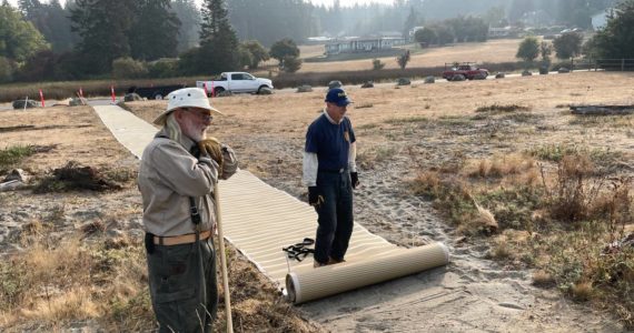 Photo provided
PaulBen McElwain of Island Beach Access and Jim Rogers of Rotary Club of Whidbey Westside roll out the new mats at Robinson Beach in Freeland.