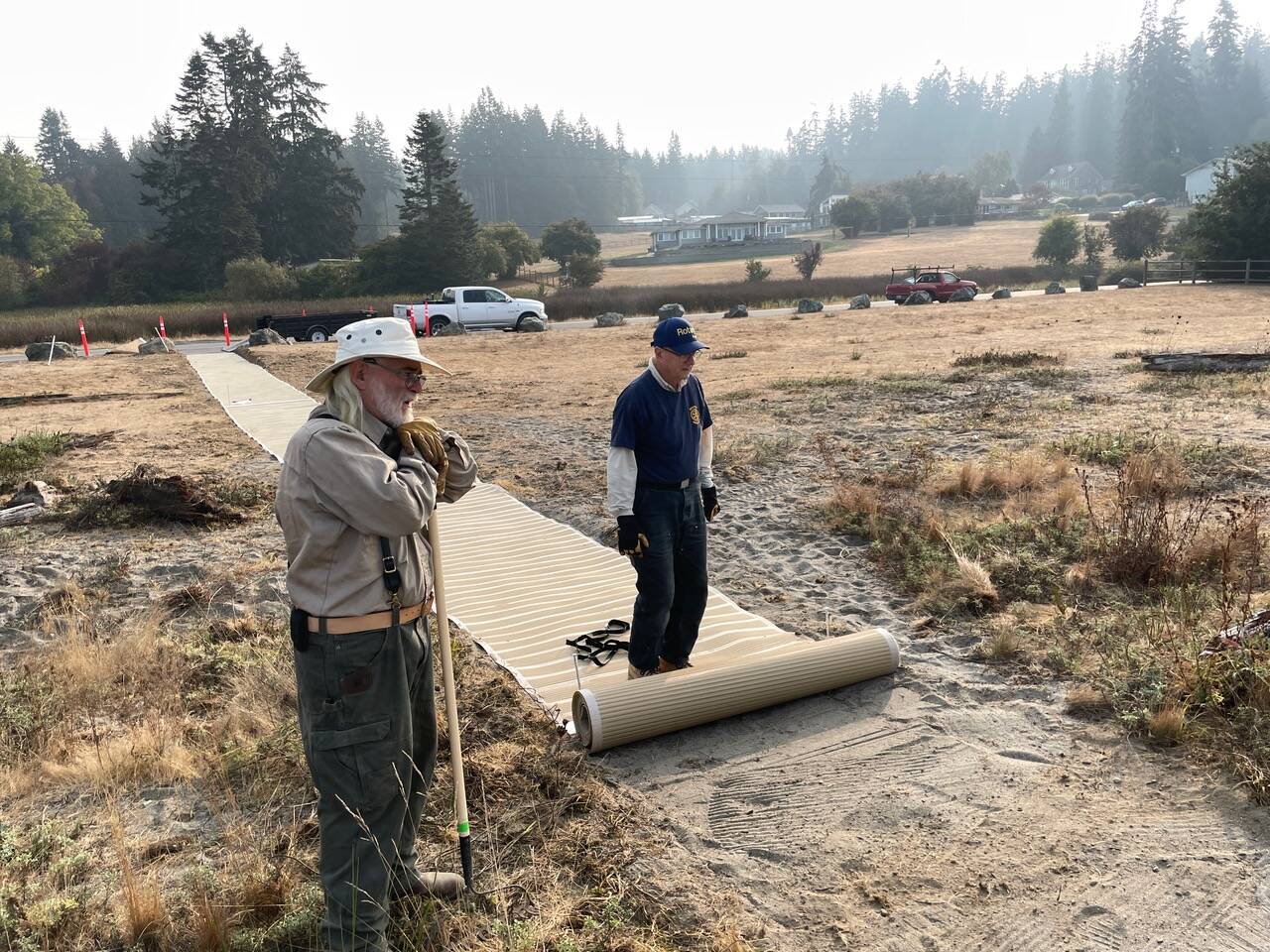Photo provided
PaulBen McElwain of Island Beach Access and Jim Rogers of Rotary Club of Whidbey Westside roll out the new mats at Robinson Beach in Freeland.