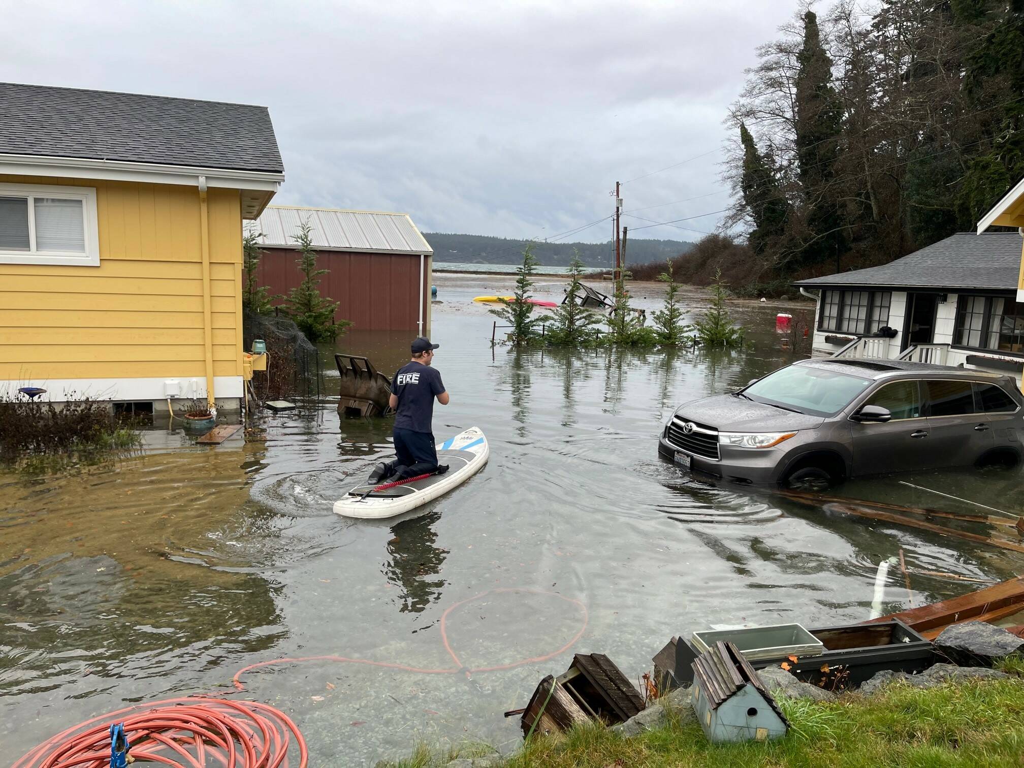 A Central Whidbey Island Fire and Rescue firefighter paddleboards between flooded homes in Greenbank. (Photo provided)