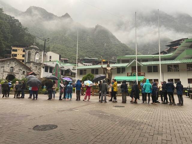 Tourists stand in line in the rain, waiting to be organized into groups for evacuation. (Photo provided)