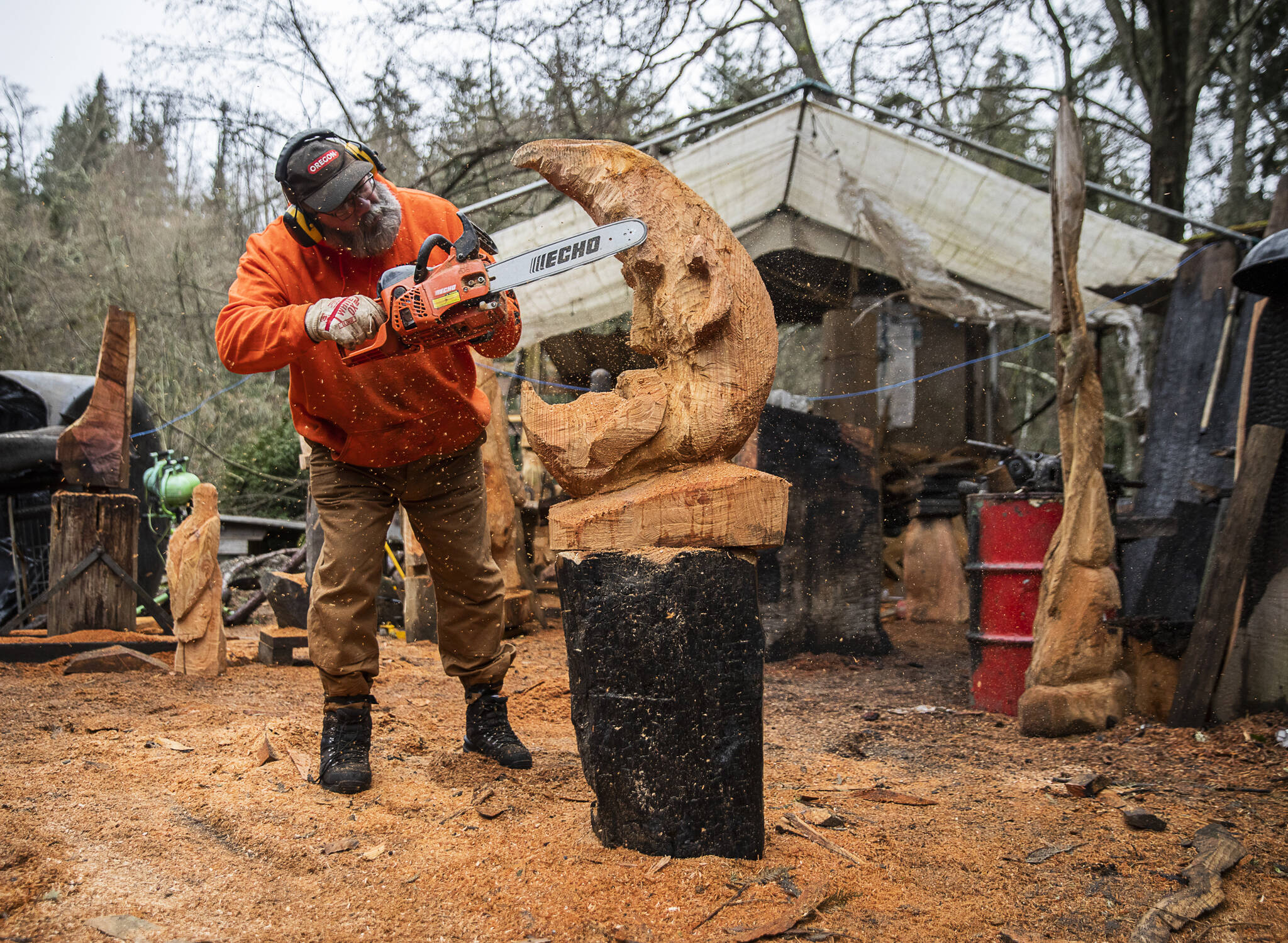 Olivia Vanni / The Herald
Steve Backus works on the details of a moon carving at his outdoor workshop in Clinton. A Dec. 2 fire destroyed his studio in the former sawmill on the 4-acre Glendale Road property that houses his Big Shot Woodcarving business and home.