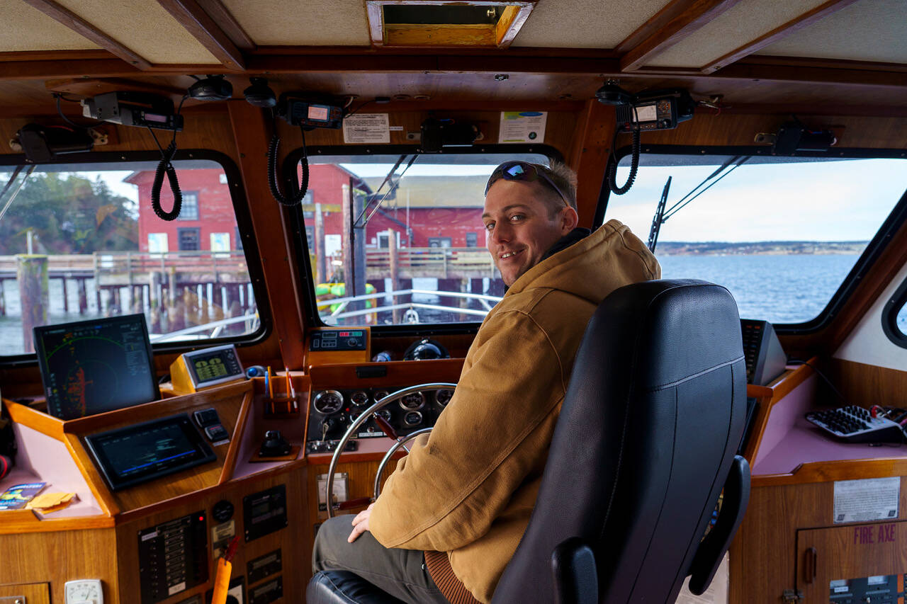 Photo by David Welton
Christopher Lewman takes the wheel of the Glacier Spirit for mussel raft tours during the Penn Cove Musselfest Sunday. The annual event, which was back at full strength, drew big crowds in Coupeville.