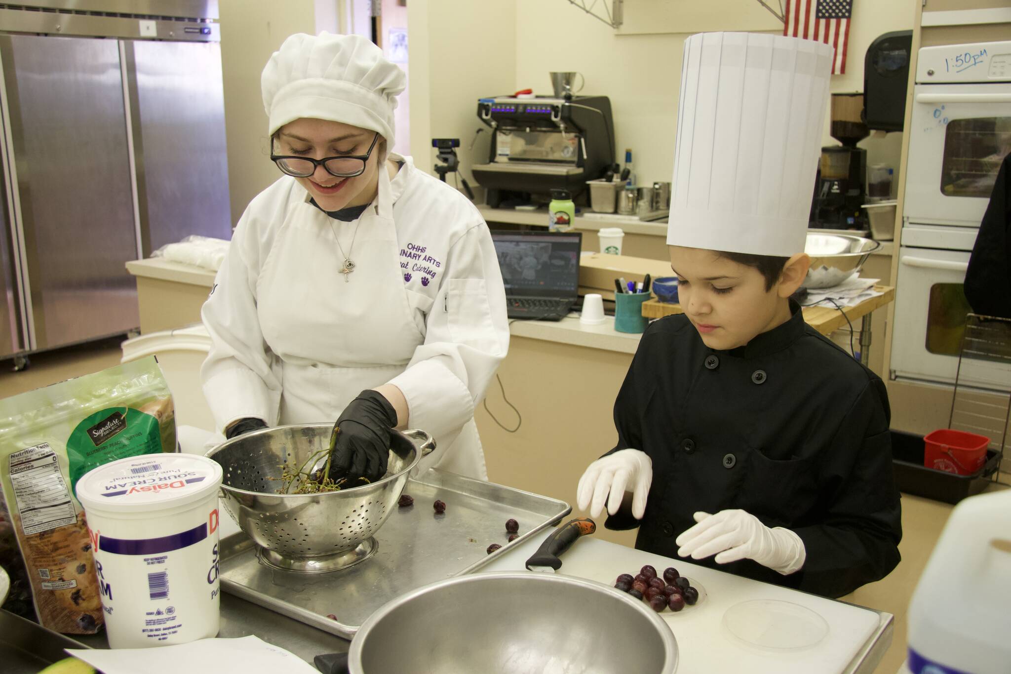Kodi Ruiz (right) prepares grapes for a fruit salad. High school student Lily Erwin assists. (Photo by Rachel Rosen/Whidbey News-Times)