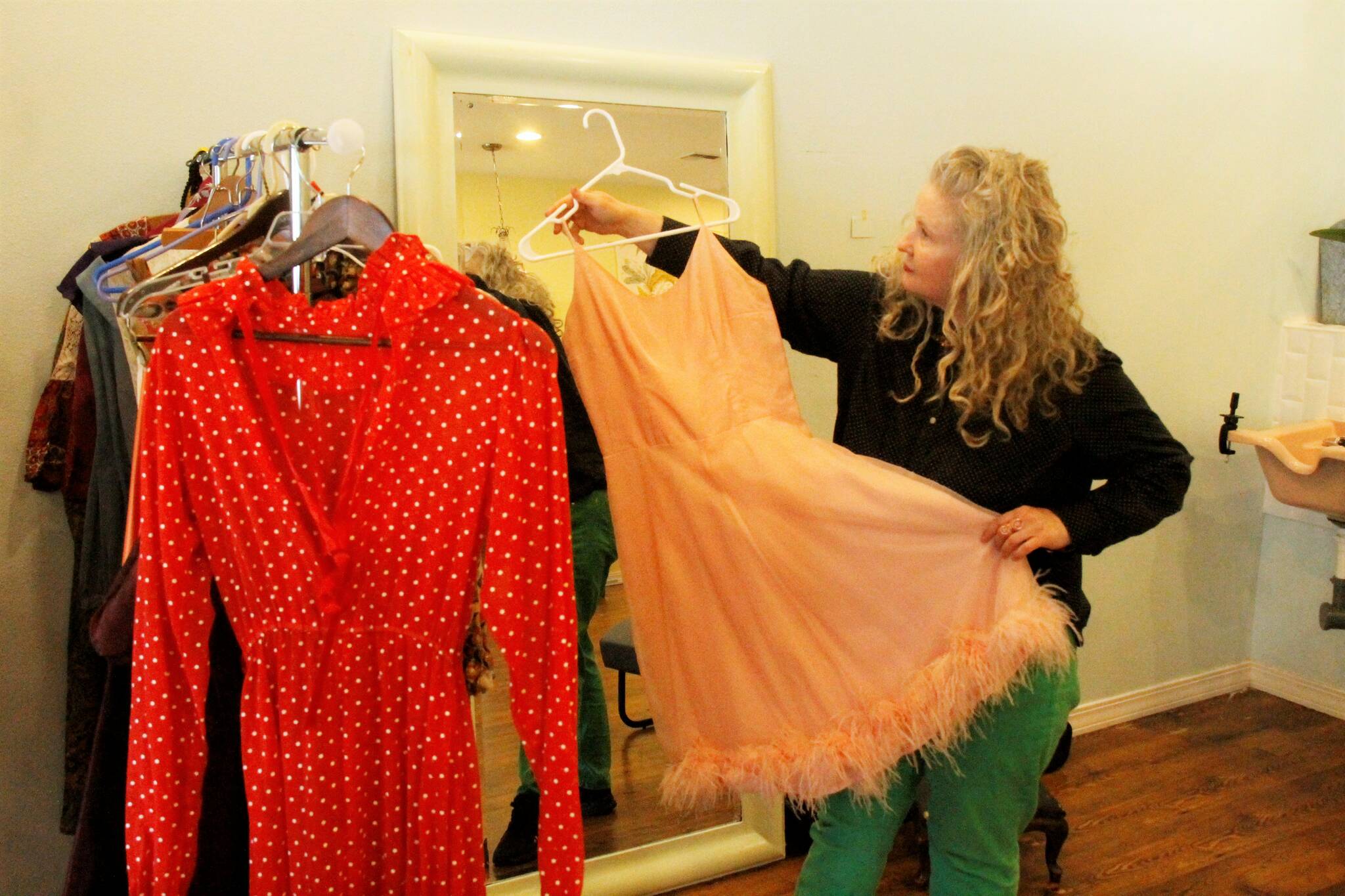 Alison Donham holds up a dress from her rack of vintage prom dresses. Clients may be asked to model an outfit. (Photo by Kira Erickson/South Whidbey Record)
