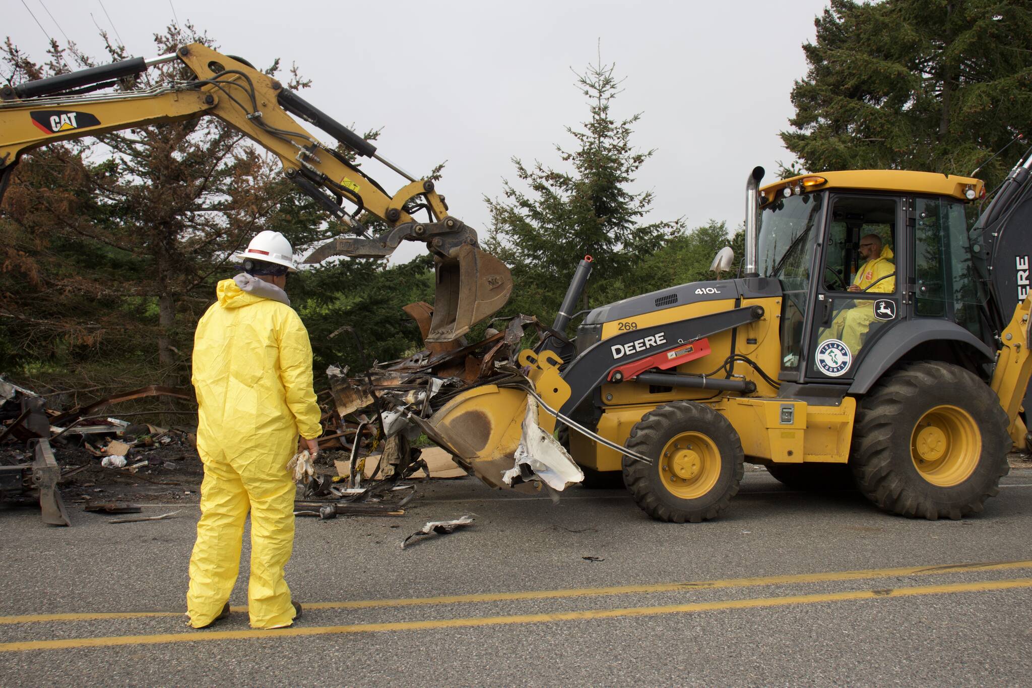 Island County employees collect the remains of a burnt-out trailer. (Photo by Rachel Rosen/Whidbey News-Times)