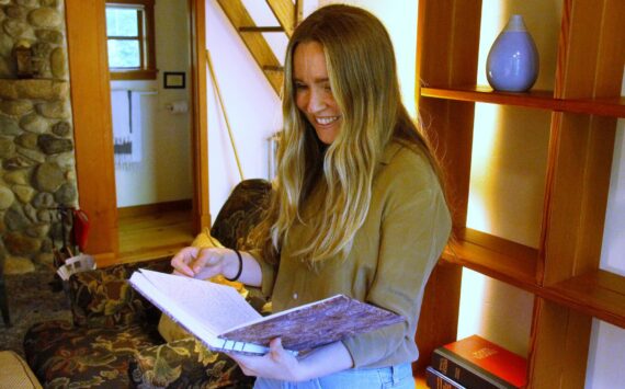 Development and Communications Specialist Nia Martin pages through a journal in one of the Hedgebrook cottages. (Photo by Kira Erickson/South Whidbey Record)