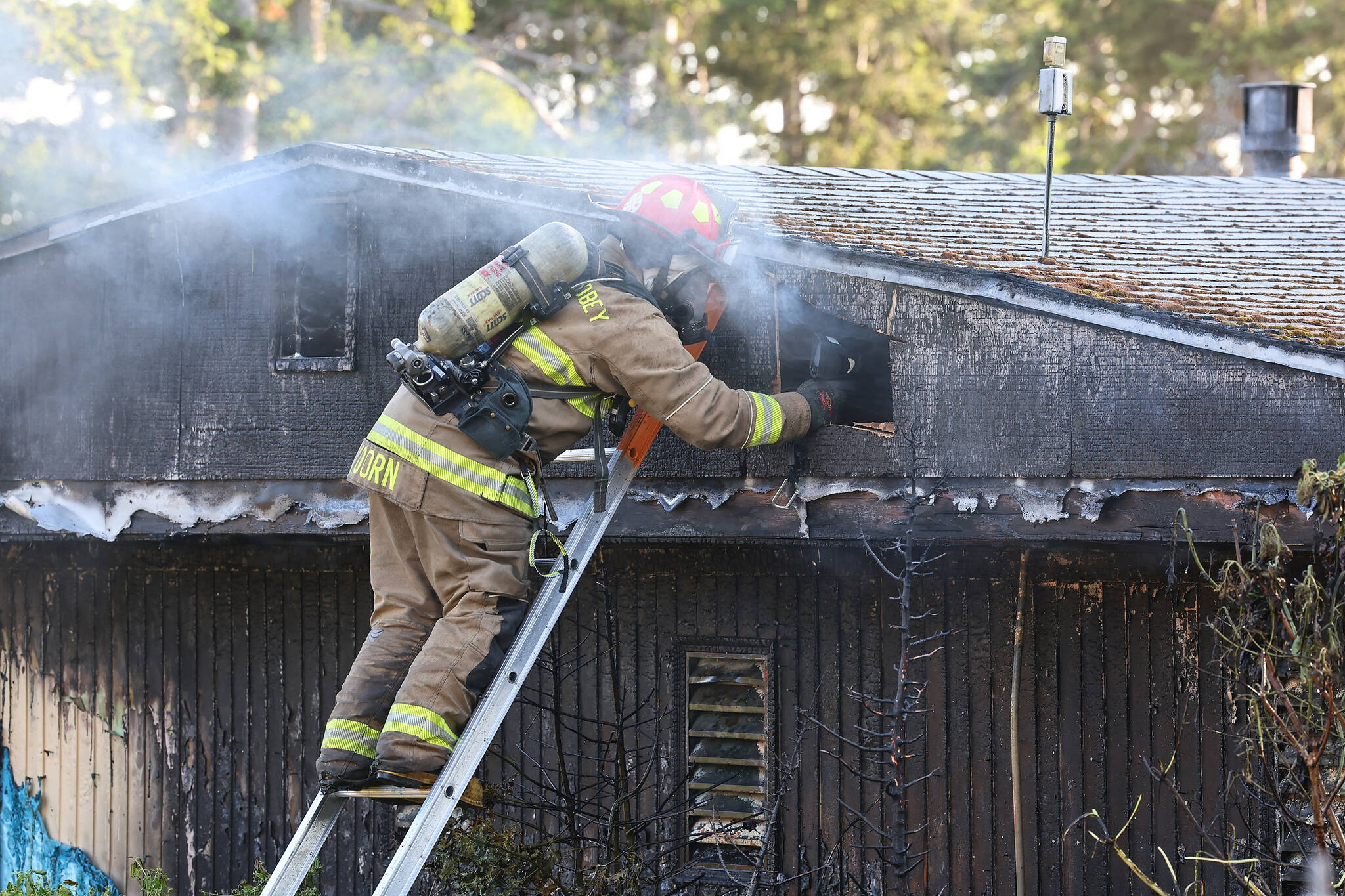 A North Whidbey Fire and Rescue firefighter works to extinguish a residential fire on Deer Park Lane May 25. (Photo by John Fisken)