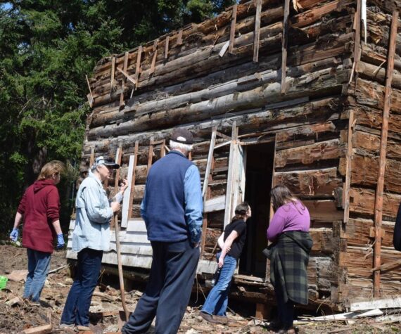 Photo by Patricia Guthrie
Marian Myszkowski, far left, looks over the cabin found hidden in the walls of an old farmhouse on her Langley property. Joining her are South Whidbey Historical Society members and students from Woodhaven School.