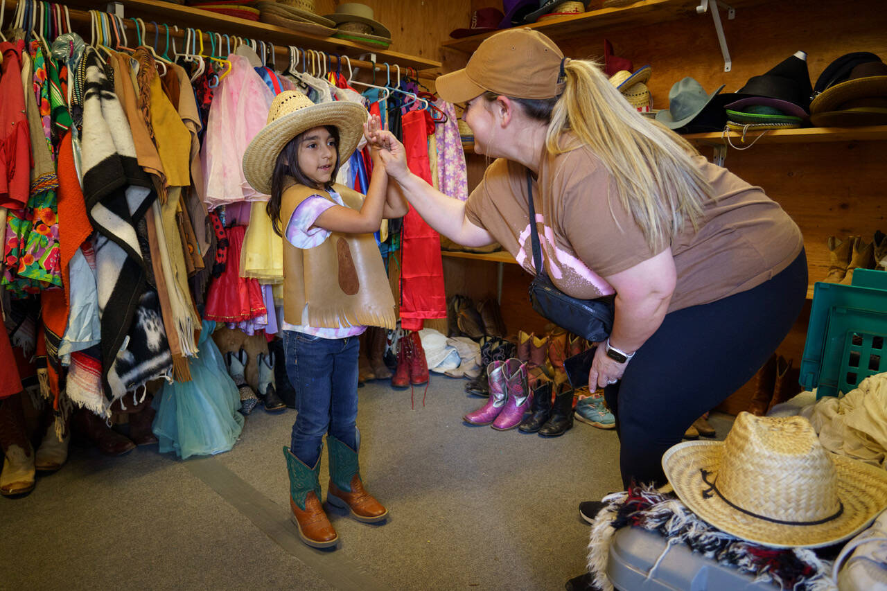 Kindergartener Elaine Trevino dons a cowgirl ensemble with assistance from Life Skills Paraeducator Dana Parry. (Photo by David Welton)
