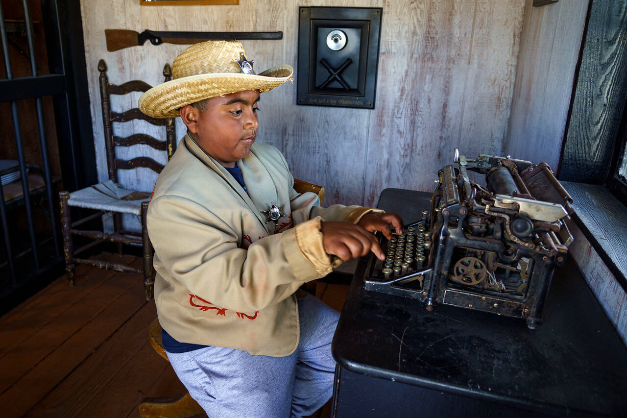 Fourth grader Marvin Rodriguez composes a message on an antique typewriter in the Cowboy Town jail. (Photo by David Welton)
