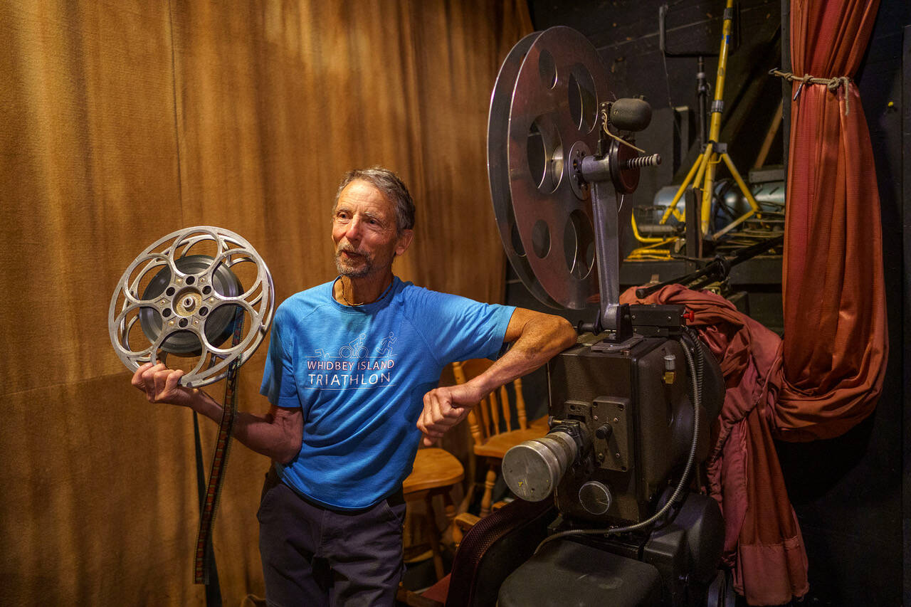 Blake Willeford stands beside the projector that The Clyde Theatre used to show films until moving to a digital format in 2011.