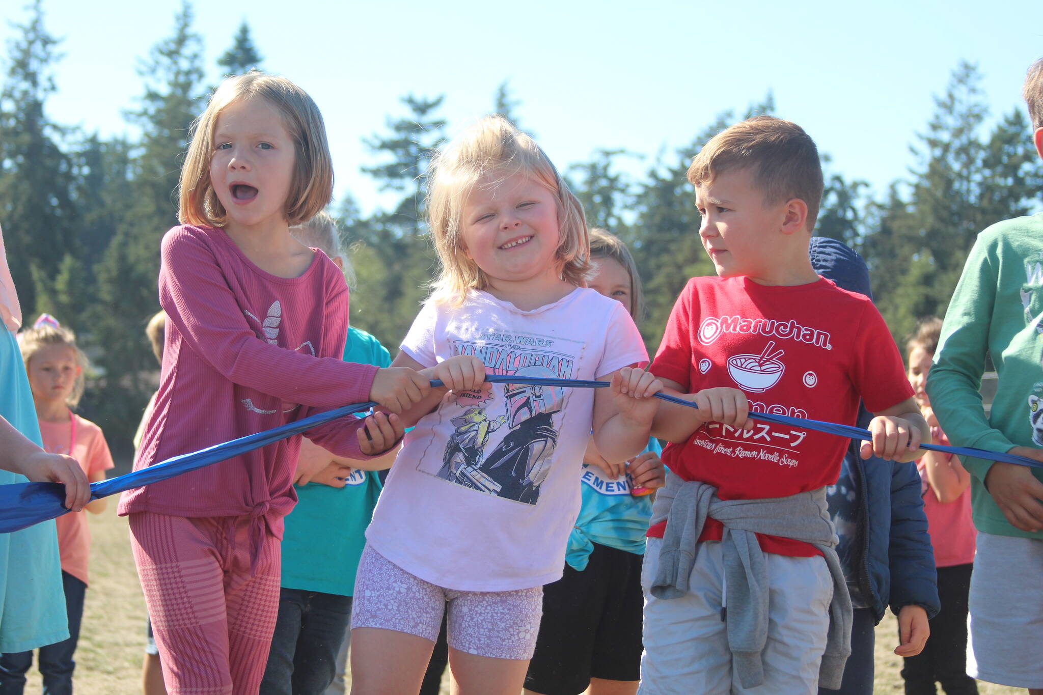 Photo by Karina Andrew/Whidbey News-Times
From left, first graders Amelia Rhodes, Chelsie Turner and Callum Macklin help hold the ribbon at the opening of the newly paved walking path at Hillcrest Elementary School Sept. 15.