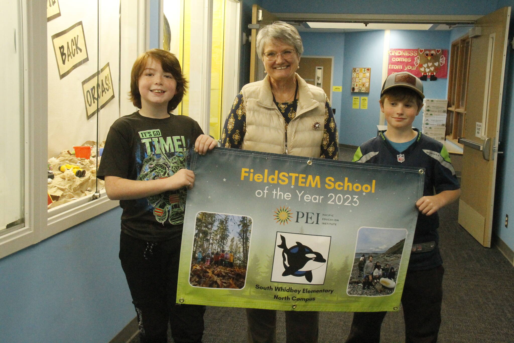 From left, David Bryant, 11, South Whidbey Elementary School Principal Susie Richards and Carter Poolman, 10, hold up a banner celebrating the FieldStem School of the Year award. (Photo by Kira Erickson/South Whidbey Record)