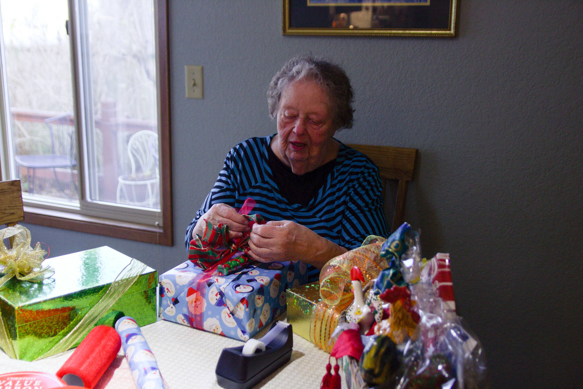 June Zacharias prepares gifts for the Holiday House at her house in Oak Harbor. Every year, she begins to prepare for the event in January, buying gift wrap paper, ribbons and more. (Photo by Luisa Loi)