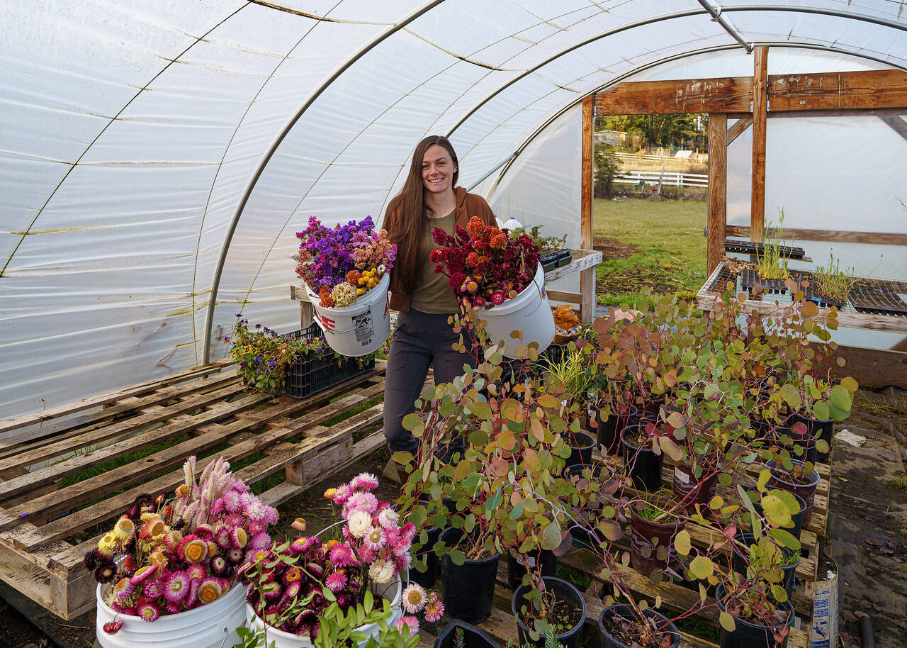 Emily Martin carries buckets of dried flowers into her hoop house. (Photo by David Welton)