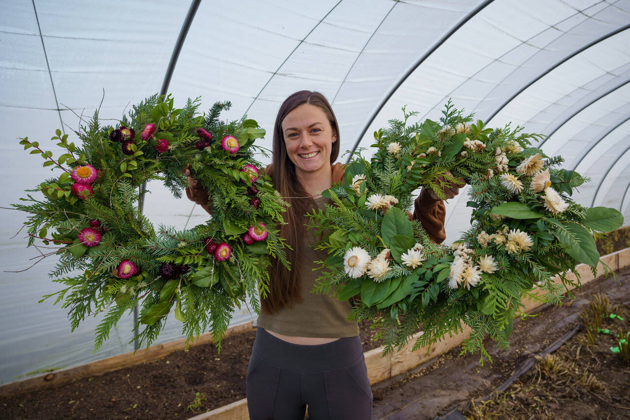 Emily Martin shows off two wreaths made from freshly foraged foliage with bits of dried flowers. (Photo by David Welton)