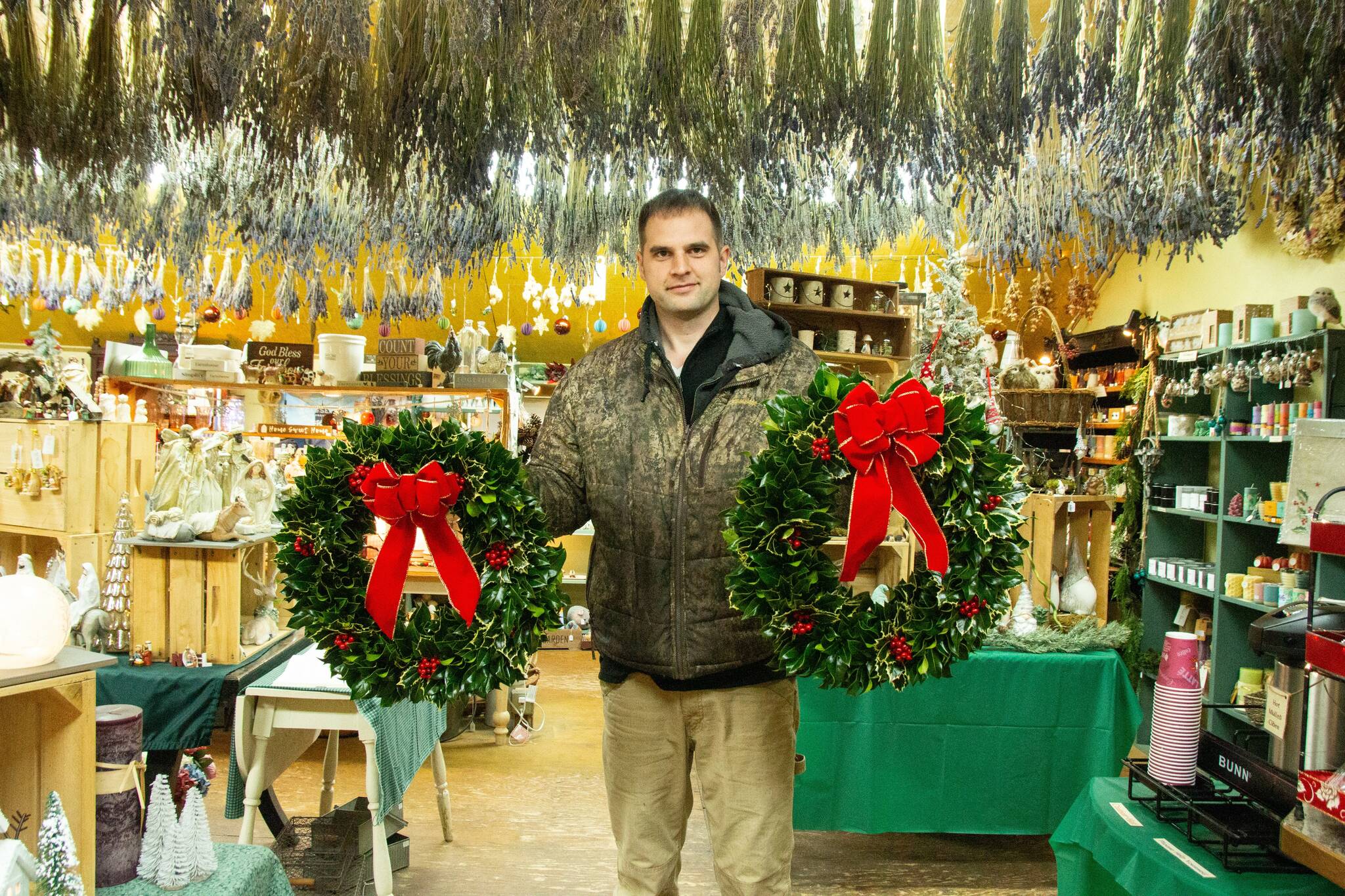 Isaiah Rawls, greens manager at A Knot in Thyme, poses with some freshly made wreaths. (Photo by Luisa Loi)