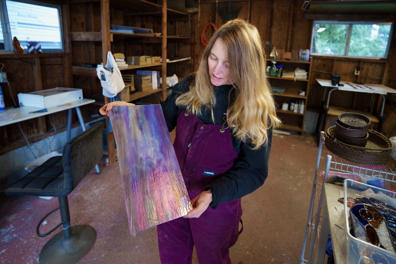 Bennett holds up a pane of iridescent purple glass. (Photo by David Welton)