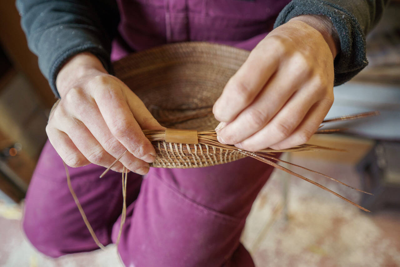 Bennett weaves together pine needles to create a basket, a process which takes several hours. (Photo by David Welton)