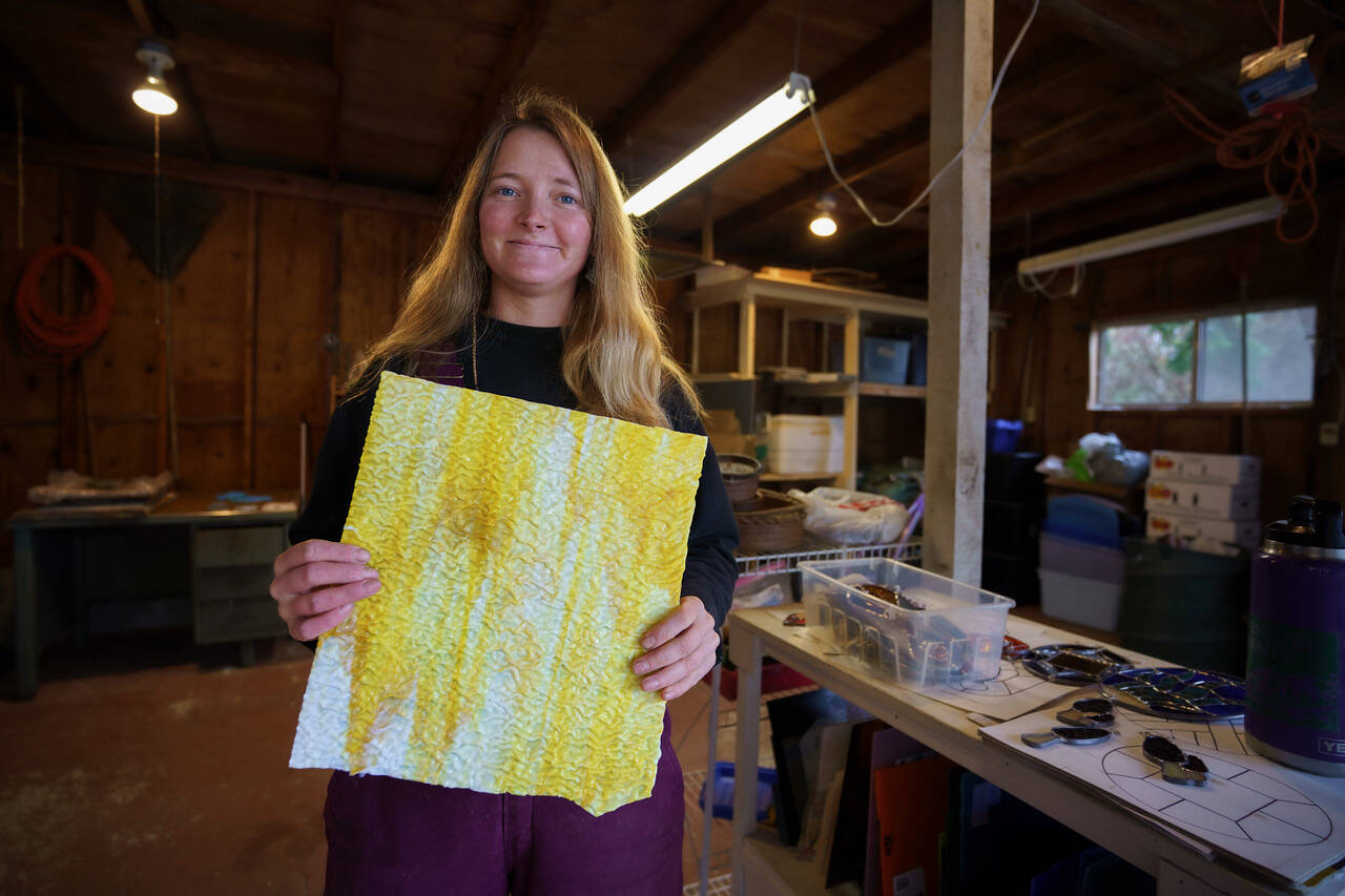 Bennett holds up a sheet of yellow glass with a wavy texture. (Photo by David Welton)