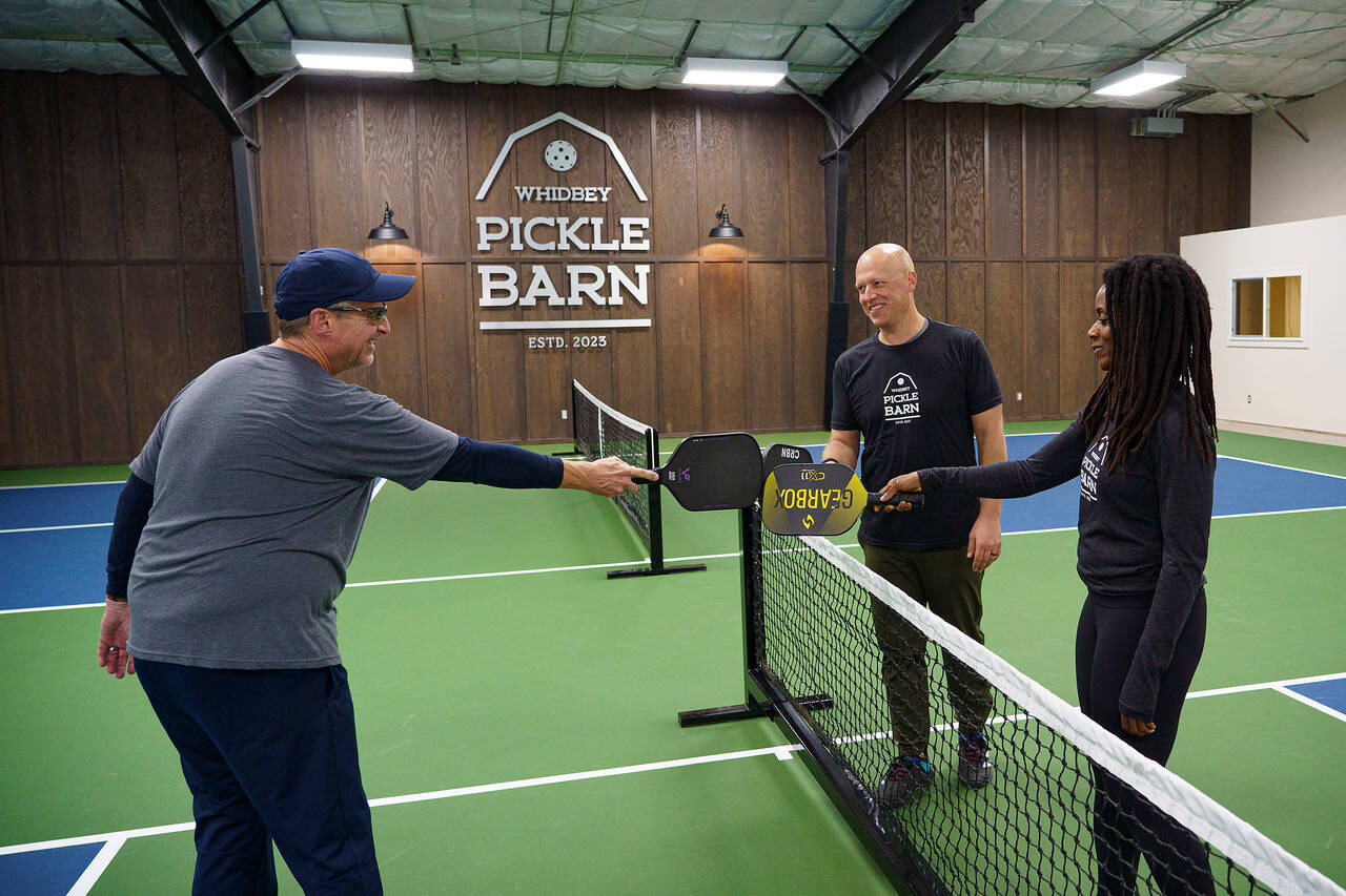 From left, Timm Sanford, Paul and Abi Tschetter tap paddles, a customary gesture after a game of pickleball. (Photo by David Welton)