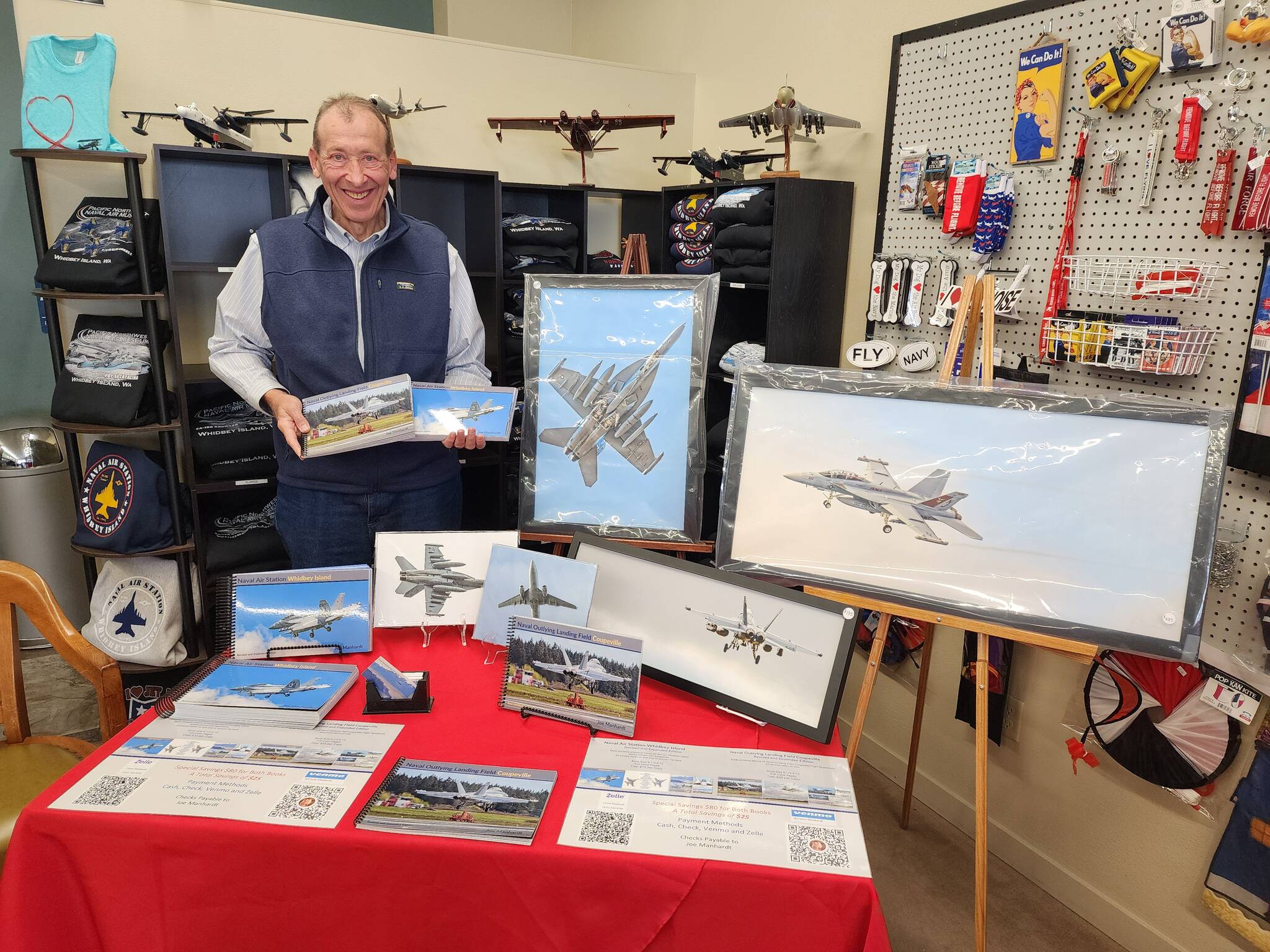 Photographer Joe Manhardt poses at his booth at the book launch of Naval Air Station Whidbey Island at Pacific Northwest Naval Air Museum on Saturday. (Photo courtesy of Pacific Northwest Naval Air Museum)
