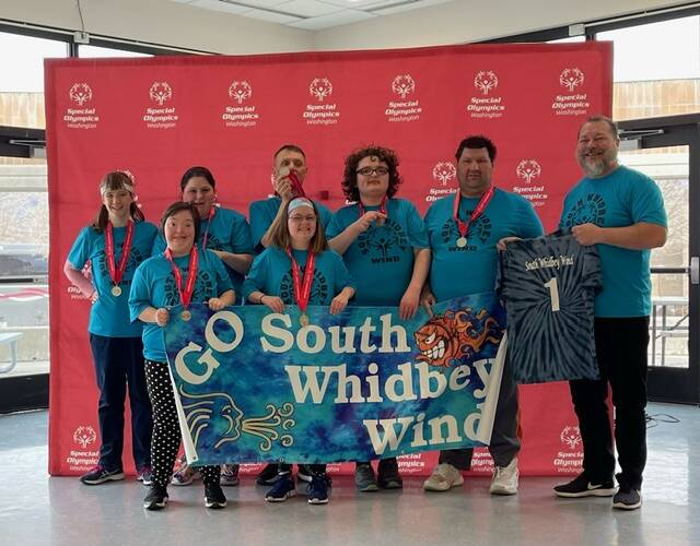 Photo provided
The South Whidbey Wind celebrates their win. Back row, from left: Julietta Cedars, Stacie Lanniers, Gregg Daily, Nicky Whitehouse, Ryan James and Coach Steve Thompson, who holds the jersey for Mark Welch, a former teammate. Front row, from left: Zoe Thompson and Maddy Acken.
