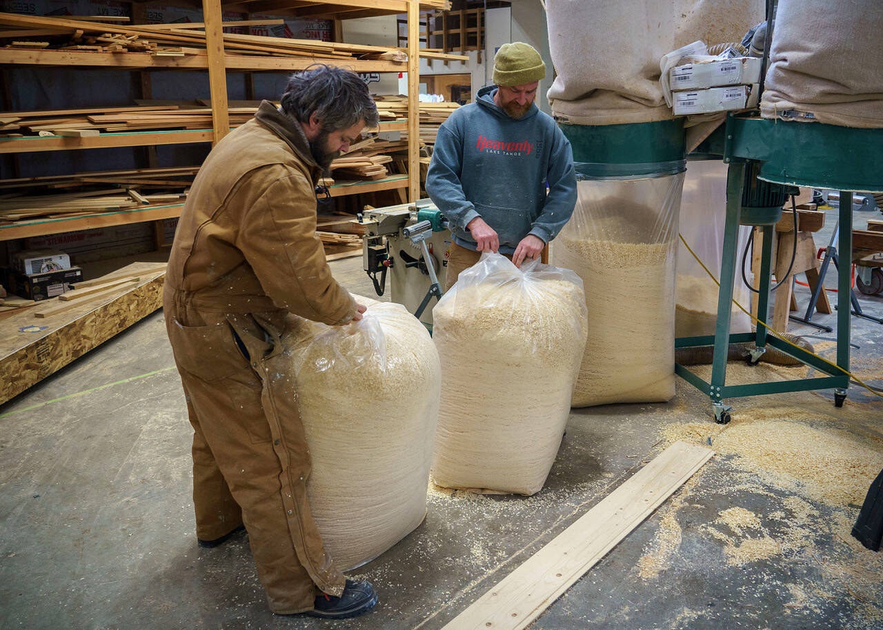Whidbey Millhouse employees Brendan McHugh, left, and Gus Gordon handle 55-gallon bags of sawdust. (Photo by David Welton)