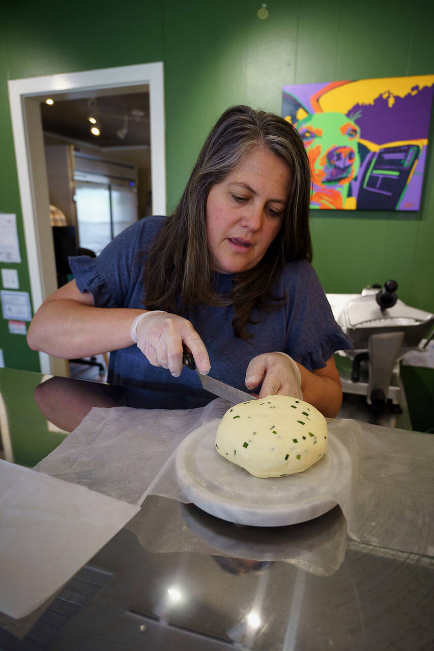 Sarah Bystrom slices a wheel of Ladysmith cheese with chives in Biercuterie, a new cheese shop she recently opened in Freeland with her husband, Brian. (Photo by David Welton)