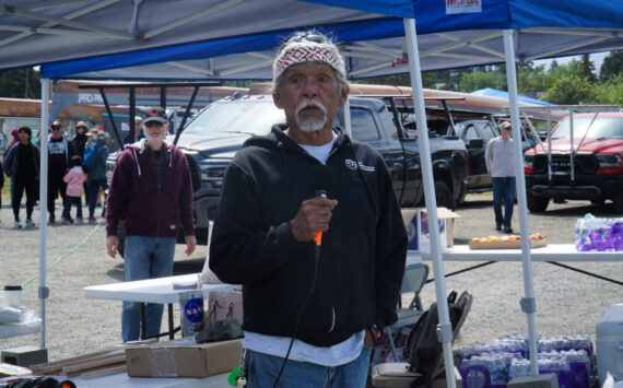 Tony Cladusbid, co-owner of the Beaver Tales Coffee franchise, announces the canoe races at the Penn Cove Water Festival on Saturday. (Photo by Sam Fletcher)