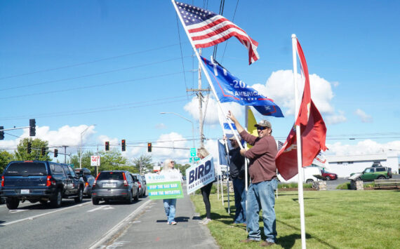 Island County Republican Party President Tim Hazelo (right) rallies with others in Oak Harbor on Thursday. (Photo by Sam Fletcher)