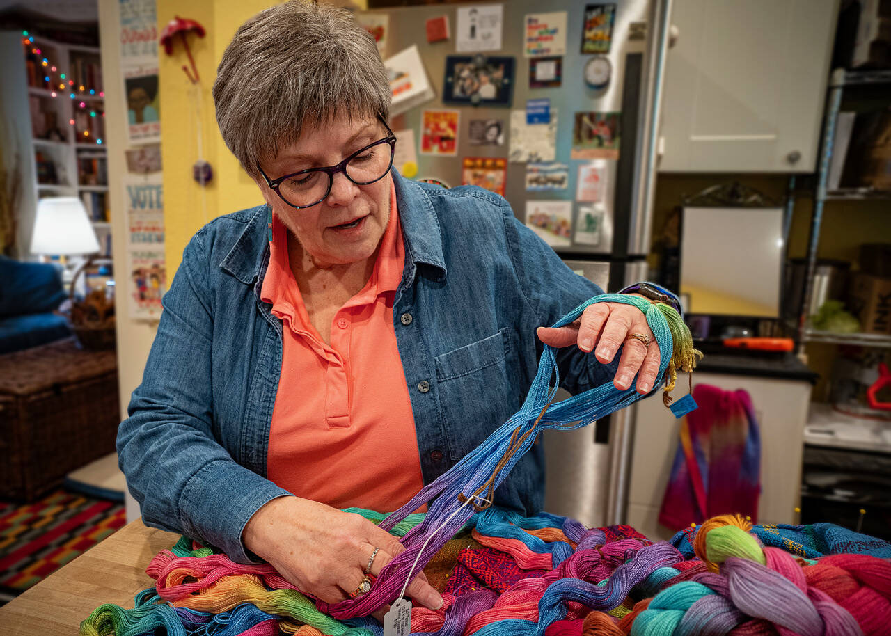 (Photo by David Welton) Danette Sulgrove spreads apart the colorful hand-dyed threads that will be woven.
