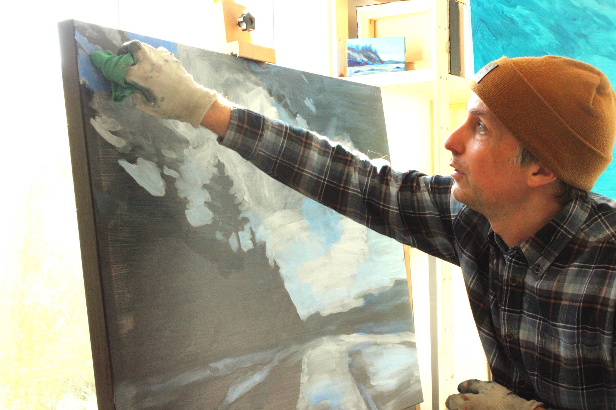 (Photo by Allyson Ballard) Haslet demonstrated his painting technique upon the <em>News-Times </em>visit, carefully dusting blue paint upon a canvas to carve out a skyline.