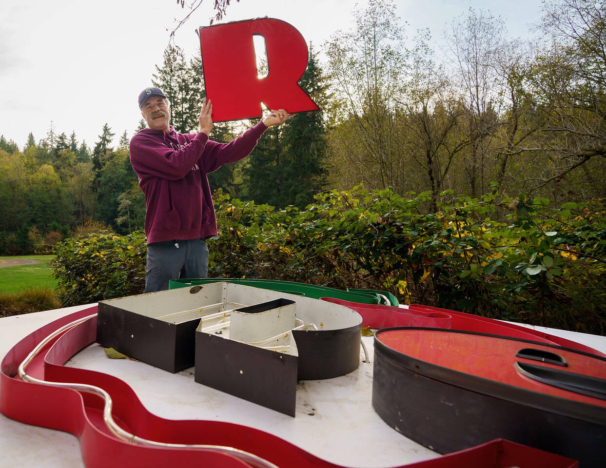 (Photo by David Welton) Clinton resident John Norris gleefully holds up the R thats part of the Kens Korner Red Apple sign. The picker managed to score the iconic grocery store sign.