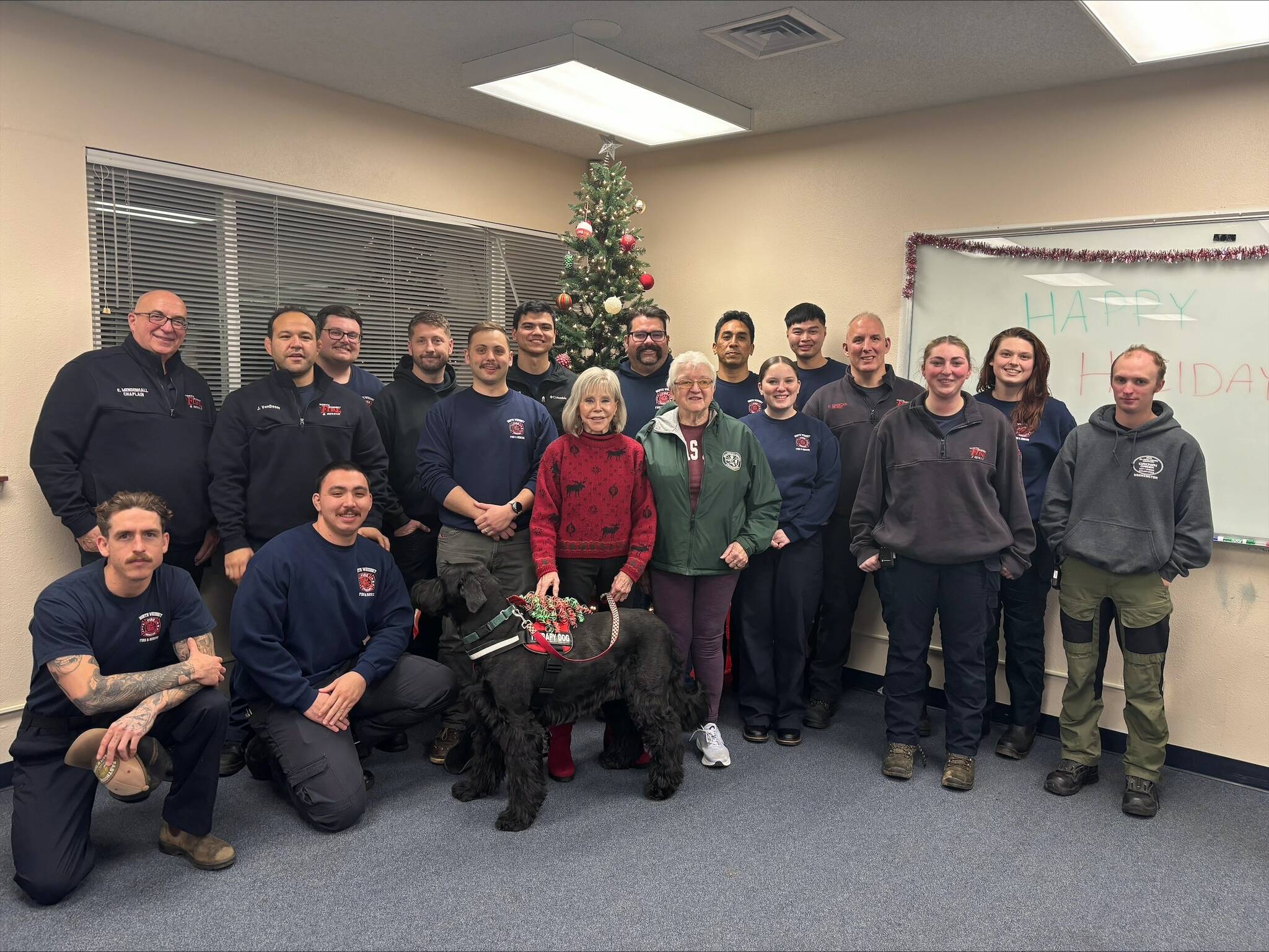 (Photo provided by North Whidbey Fire and Rescue) Barbara Kurse, accompanied by her emotional support dog celebrity, Cozmo, and friend Pat LaMonte, delivered a generous spread of treats to the firefighters last Monday.
