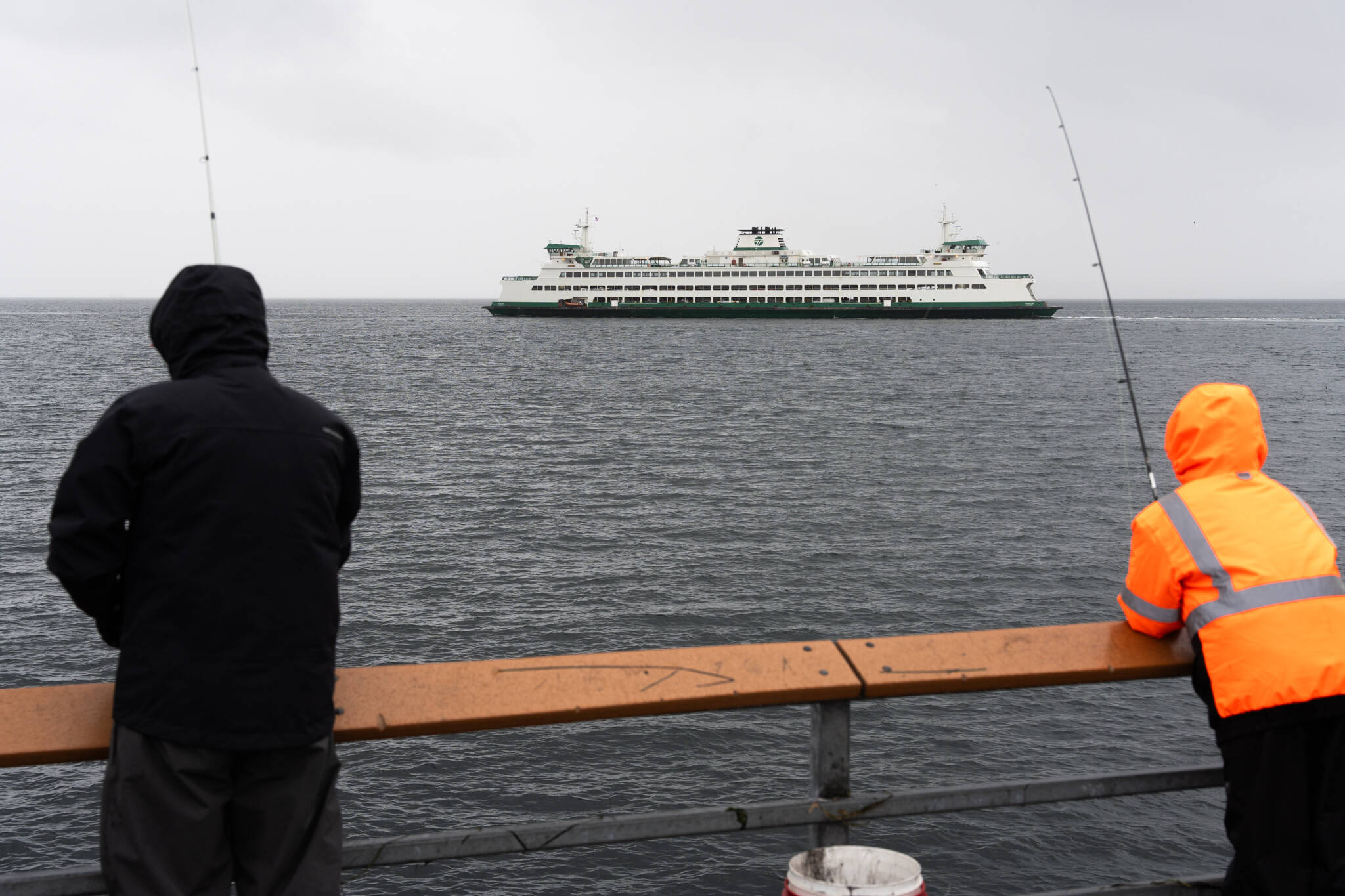 Will Geschke / The Herald
Amid cold, wind and rain, people fish along a pier in Edmonds while they watch a state ferry travel to Kingston on Nov. 17 in Edmonds.