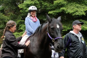 Swedish Medical Center patient Maria Peccorini is all smiles as she starts to ride a horse with the help of Equestrian Crossings workers. Peccorini has multiple sclerosis.