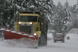 An Island County snow plow works to clear Ewing Road late Thursday. County officials expect to declare a “state of emergency” on Monday.