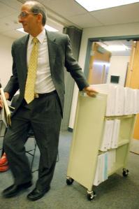 Island County Prosecutor Greg Banks wheels in a cart loaded with documents from a murder case to the commissioners’ work session. Banks is asking for additional funding for staff to help address a large workload.