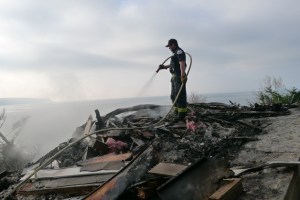 A firefighter from Central Whidbey Fire and Rescue douses a hotspot in the wreckage of a home that burned to the ground Sunday night.