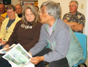 Marcia and Clyde Monma offer Port of South Whidbey commissioners some photos they took of the Dorothy Cleveland trail at Possession Point Waterfront Park last week.