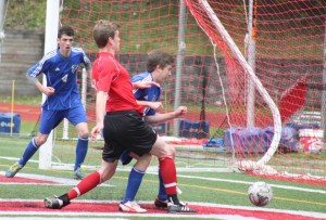 South Whidbey junior defender Anders Bergquist is hit as he tries to block King’s junior Josh Alexander’s goal in the second half of the 1A District 1 title match May 10. Falcon junior Tom Swanson looks on from the far post.