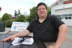 Langley mayoral candidate Thomas Gill sits alone at a table on the Second Street plaza Monday night. He had planned a meet-and-greet