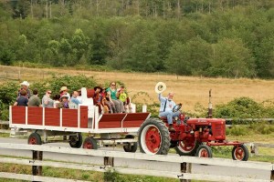 Steve Maynard of Greenbank waves his hat and drives a tractor full of children at the M-Bar-C Ranch. The ranch will hold a fundraiser Sept. 19-21.