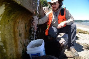 Justin Brooks takes a water measurement at the base of a landslide at Brighton Beach. The University of Washington graduate student is hoping to figure out just what caused the slide and others.