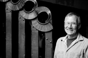 Island artist Jeff Holtby stands next to the hand-forged gate he helped create.