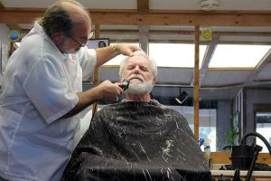 Island Headquarters owner Jeffrey Wood trims Clinton resident Gary Hansen’s beard from Wood’s small “man cave.”