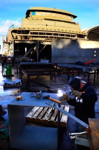 Nichols Brothers Boat Builder worker James Pease welds before a backdrop of the state’s new 144-car ferry. Construction of the superstructure is on time and it’s expected to be barged to Seattle in February.